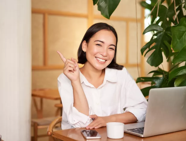 stylish-young-entrepreneur-girl-with-laptop-sitting-cafe-pointing-finger-advertisement-banner