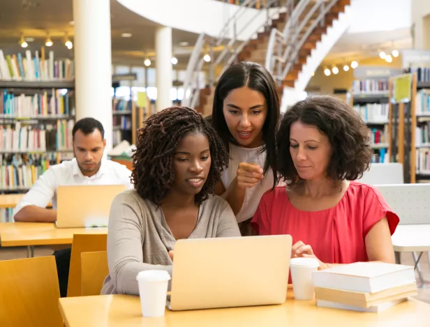 smiling-women-working-with-laptop-public-library